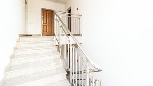 Una escalera con barandilla, una puerta de madera y una pared blanca.
