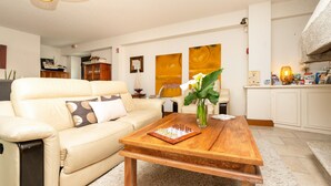 A living room with a beige sofa, a wooden coffee table, and a chessboard.