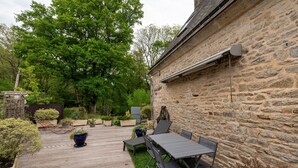 A stone building with a wooden deck, outdoor seating, and potted plants. - Room 'Chambre Campagne' with Shared Pool, Shared Terrace and Wi-Fi (Saint-Avé)