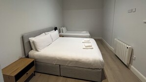 Une petite chambre propre, avec un lit simple, une table de chevet et un radiateur.