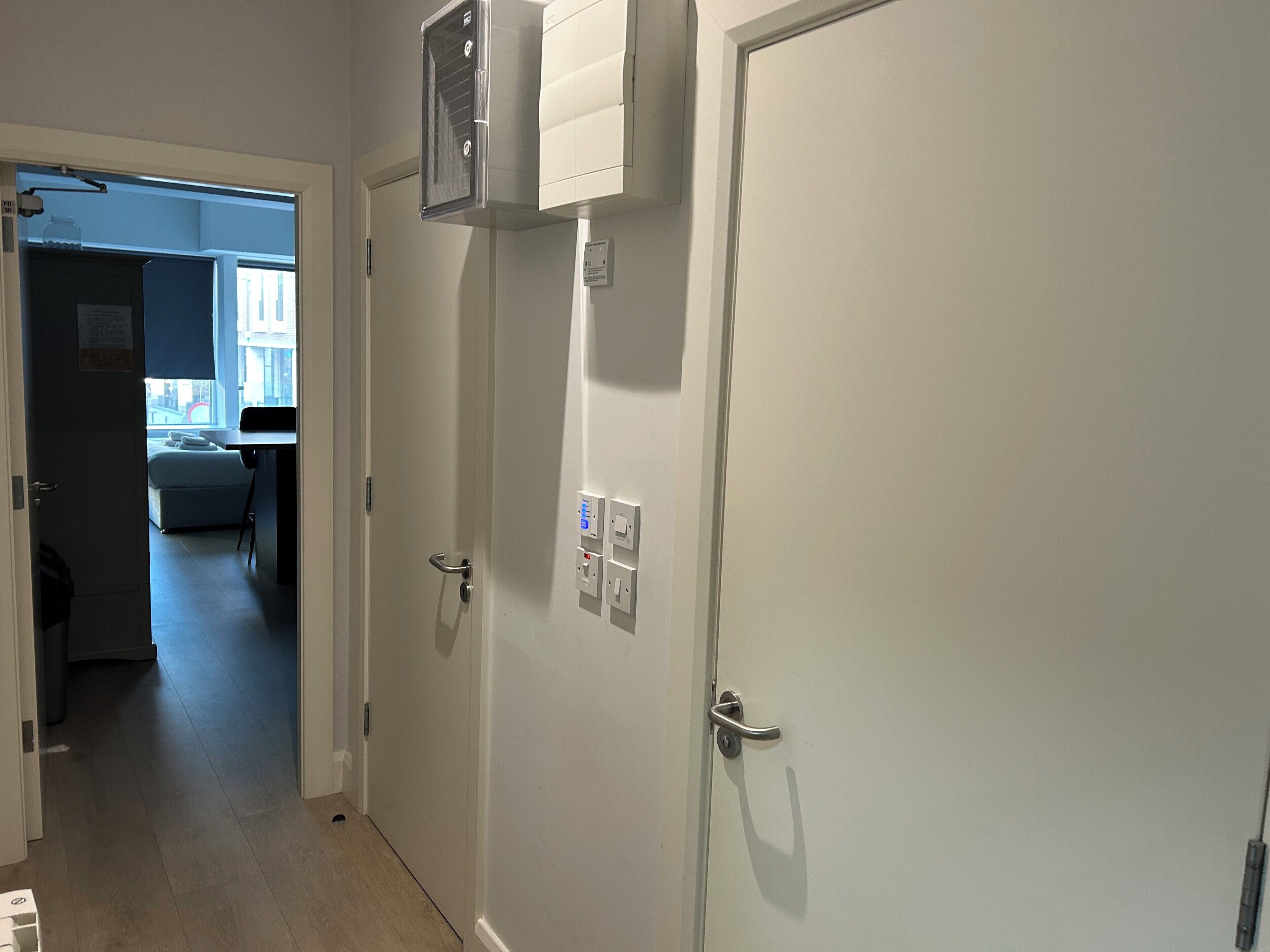 A hallway with a door leading to a bedroom, a small kitchenette, and a window with a view.