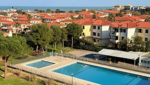 En swimmingpool med fri utsikt över det omgivande bostadsområdet och havet i bakgrunden.