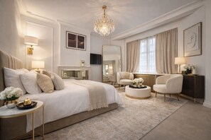 A bedroom with a large bed, bedside tables, a chandelier, a television, and a fireplace. - Luxury Pad for Couples Next to Paddington Station (London)