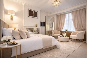 Ein Schlafzimmer mit einem großen Bett, Nachttischen, einem Spiegel, einem Fernseher und einem Fenster mit Vorhängen.
