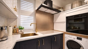A modern kitchen with a sink, stove, oven, and washing machine. - Luxury Pad for Couples Next to Paddington Station (London)
