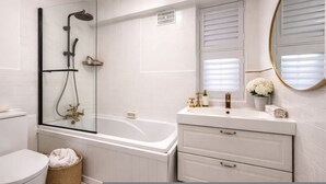 A modern bathroom with a glass-enclosed shower, a freestanding bathtub, a vanity with a mirror, and a toilet. - Luxury Pad for Couples Next to Paddington Station (London)