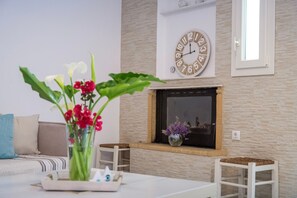 Ein Wohnzimmer mit Kamin, einer Uhr und einer Vase mit Blumen.