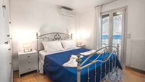 Un dormitorio con cama, mesitas de noche, ventana con vistas y aire acondicionado.