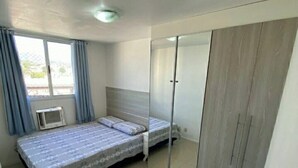 Une chambre avec deux lits, un placard à portes coulissantes et une fenêtre avec des rideaux.