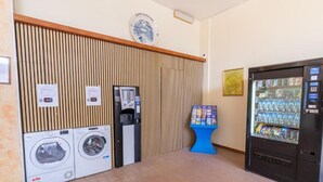 A public restroom with a vending machine, a blue information stand, and a wall-mounted plate. - Only Room Hotel  (Lido di Savio)