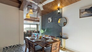 Comedor con una mesa de madera dispuesta para cuatro, un ventilador de techo y vista a otra habitación.