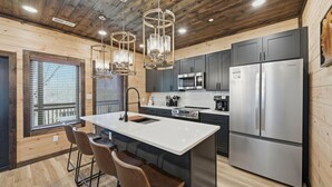 A modern kitchen with a central island, stainless steel appliances, and wooden accents. - NEW Build - Smokies Haven w/ Hot Tub, Games, MORE (Pigeon Forge)