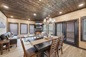 Un interior acogedor con comedor, chimenea, techo de madera y ventanas amplias.