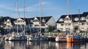 Un port de plaisance où sont amarrés de nombreux voiliers, entouré d’immeubles à plusieurs étages dotés de balcons.