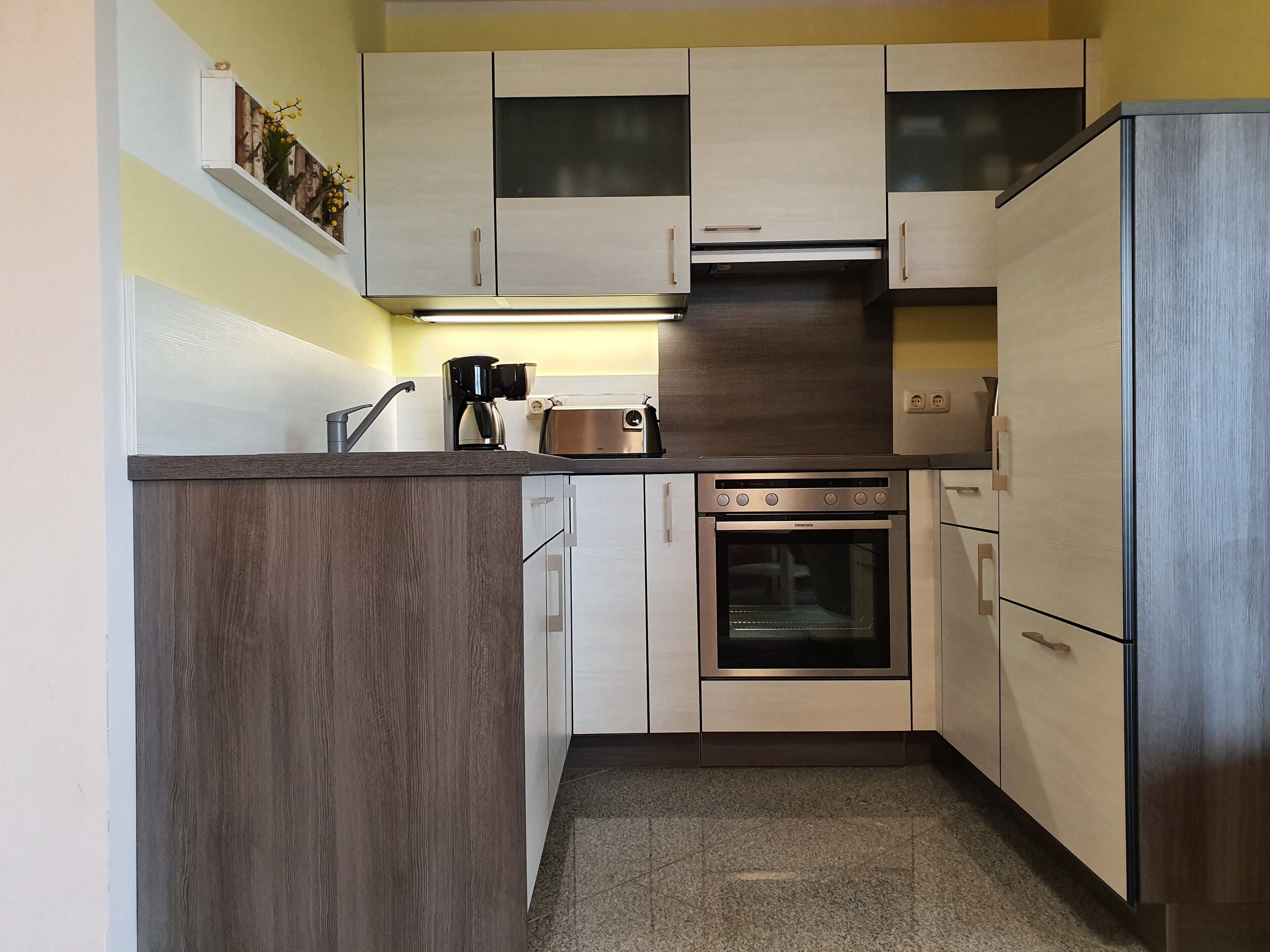 A compact kitchen with a built-in oven, a coffee maker, and a toaster.