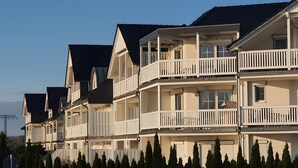 Une rangée d’immeubles à plusieurs étages, dotés de balcons, qui semblent être des appartements résidentiels, avec un ciel dégagé en arrière-plan.