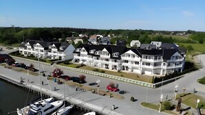 Un hôtel situé au bord de l’eau, doté de nombreux balcons, d’un port de plaisance et d’une route menant à l’établissement.