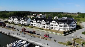 A waterfront hotel with multiple balconies, a marina, and a road leading to the property.