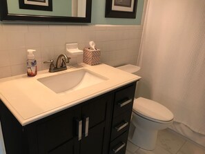 A bathroom with a white sink, dark cabinets, a toilet, and a shower curtain. - 2 BR, 2 BA Townhome in Ormond By the Sea (Ormond Beach)