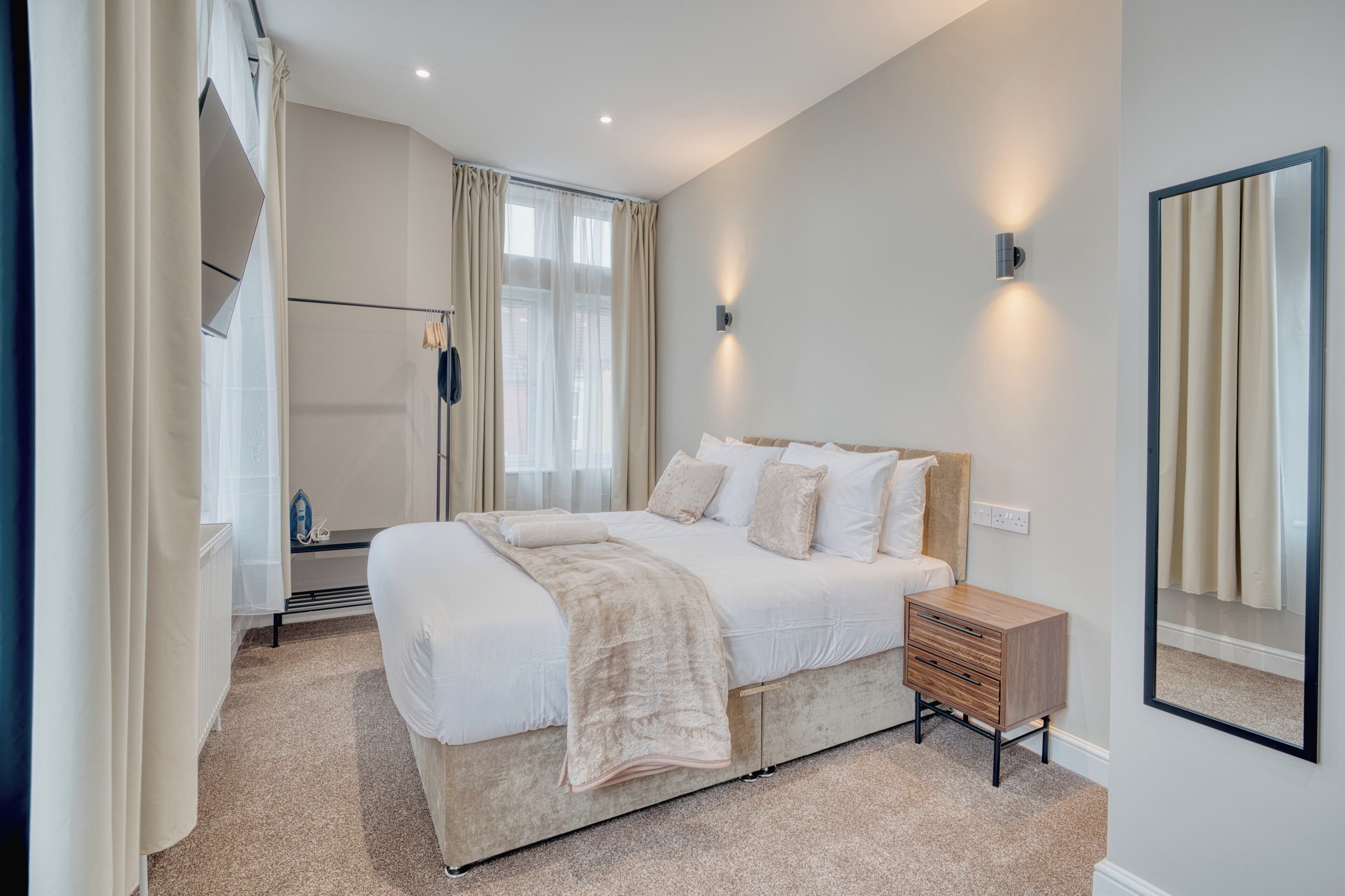 A bedroom with a bed, bedside table, and a mirror.