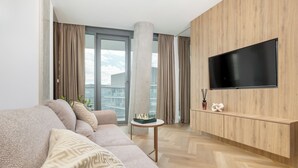 Uma sala de estar moderna com sofá, mesa de centro, TV de tela plana e vista para a cidade.