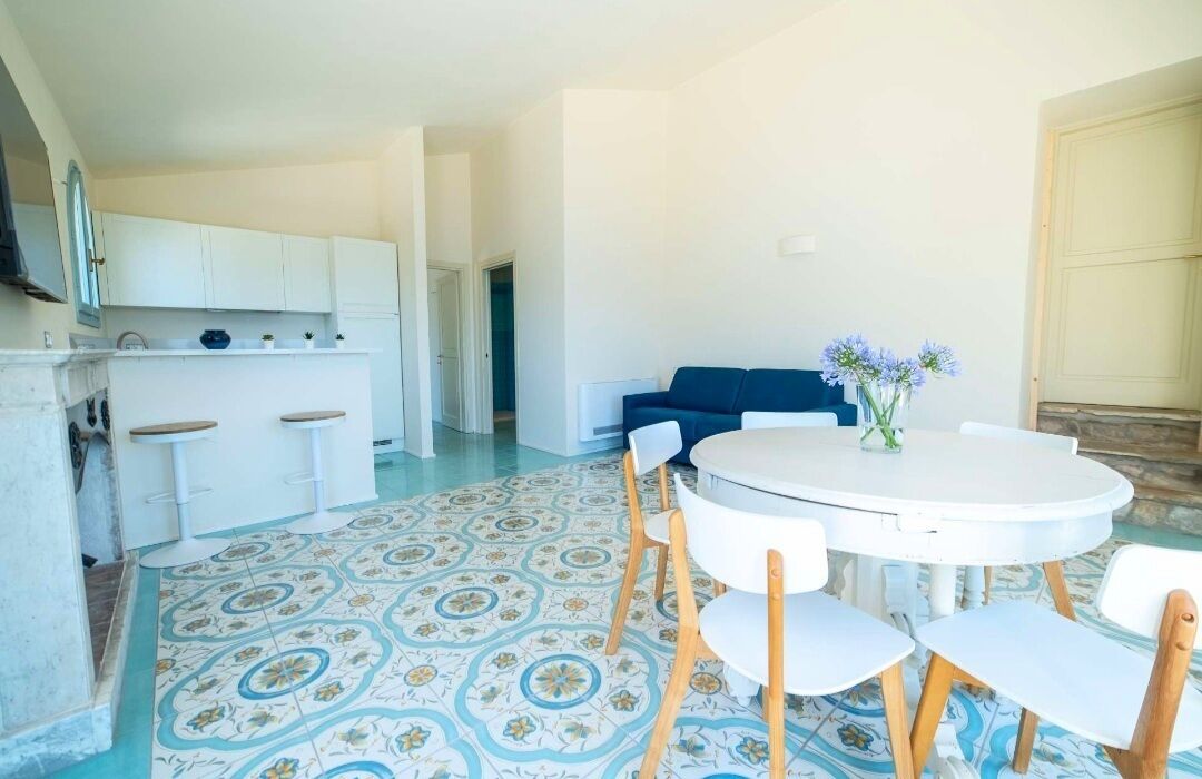A dining area with a round table, white chairs, and a blue sofa.