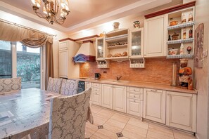 A kitchen with a dining table, chairs, cabinets, and a brick backsplash.