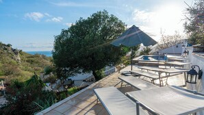 A terrace with outdoor seating and a view of the sea.