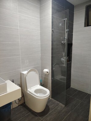 A modern bathroom with a toilet, shower, and a glass-enclosed shower area. - The Luxe Suites at Trion KL (Kuala Lumpur)