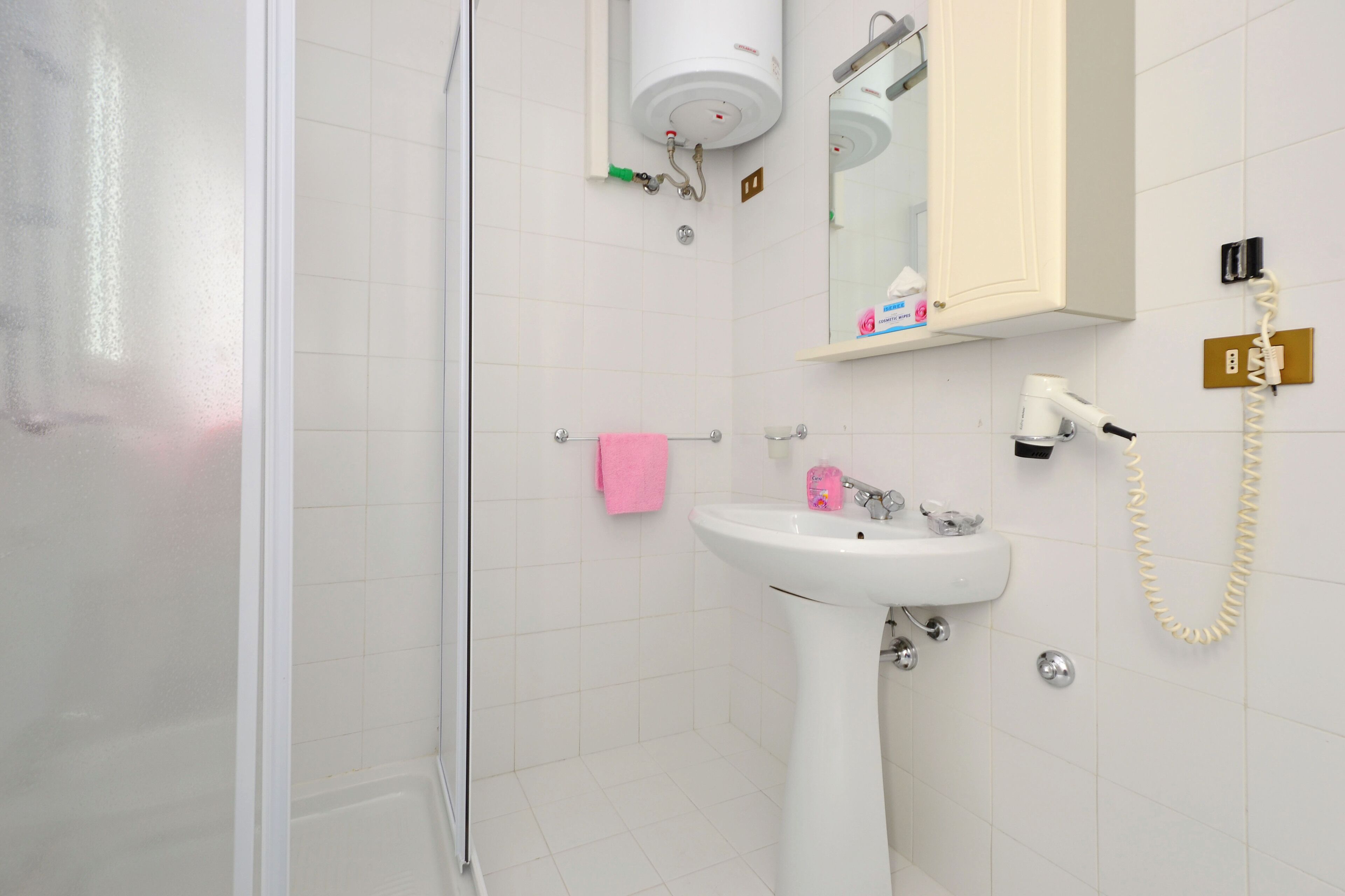 A bathroom with a white sink, a mirror, a towel rack, and a shower.