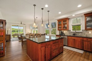 A spacious kitchen with a large island, wooden cabinets, and a dining area with a view. - Summer Deal Poipu 3BR Condo Near Kiahuna Beach Resort Pool (Koloa)