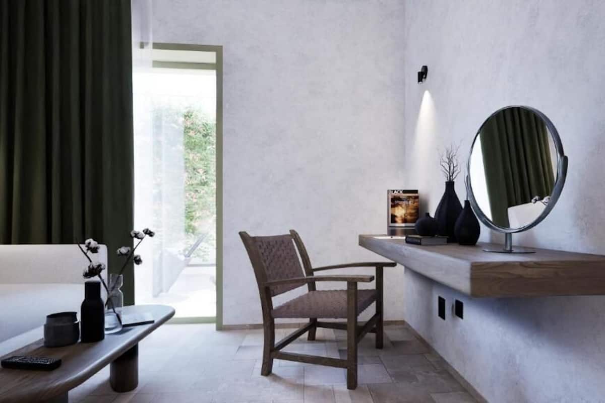 Une pièce moderne comprenant un canapé, un fauteuil, une table basse, un miroir et une étagère avec un livre.