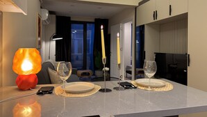 Ett modernt matområde med ett bord dukat för två personer, ett tänt ljus och en lampa.