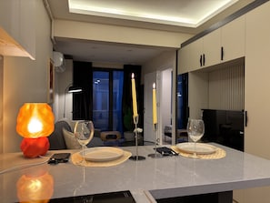 Ein moderner Essbereich mit einem Tisch für zwei Personen, einer Kerze und einer Lampe.