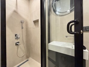 Ein Duschbereich mit Glaswänden, einer Handbrause und einer fest installierten Bedienkonsole.