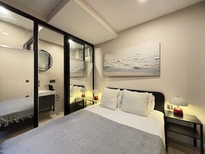 Ein Schlafzimmer mit Bett, Nachttischen, einem Spiegel und einem Bild an der Wand.