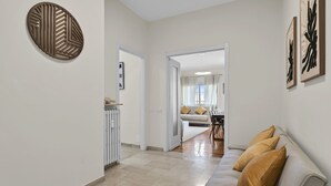 Ein Flur mit Heizkörper, einer Couch mit Kissen und einem Essbereich im Hintergrund.