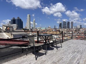 Eine Dachterrasse mit Blick auf eine Stadtlandschaft, darunter Hochhäuser und ein klarer Himmel.