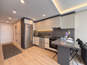 A modern kitchen with a built-in refrigerator, dishwasher, and a dining area with a table and chairs. - Chic & Cozy 2BR – Nişantaşı (Istanbul)