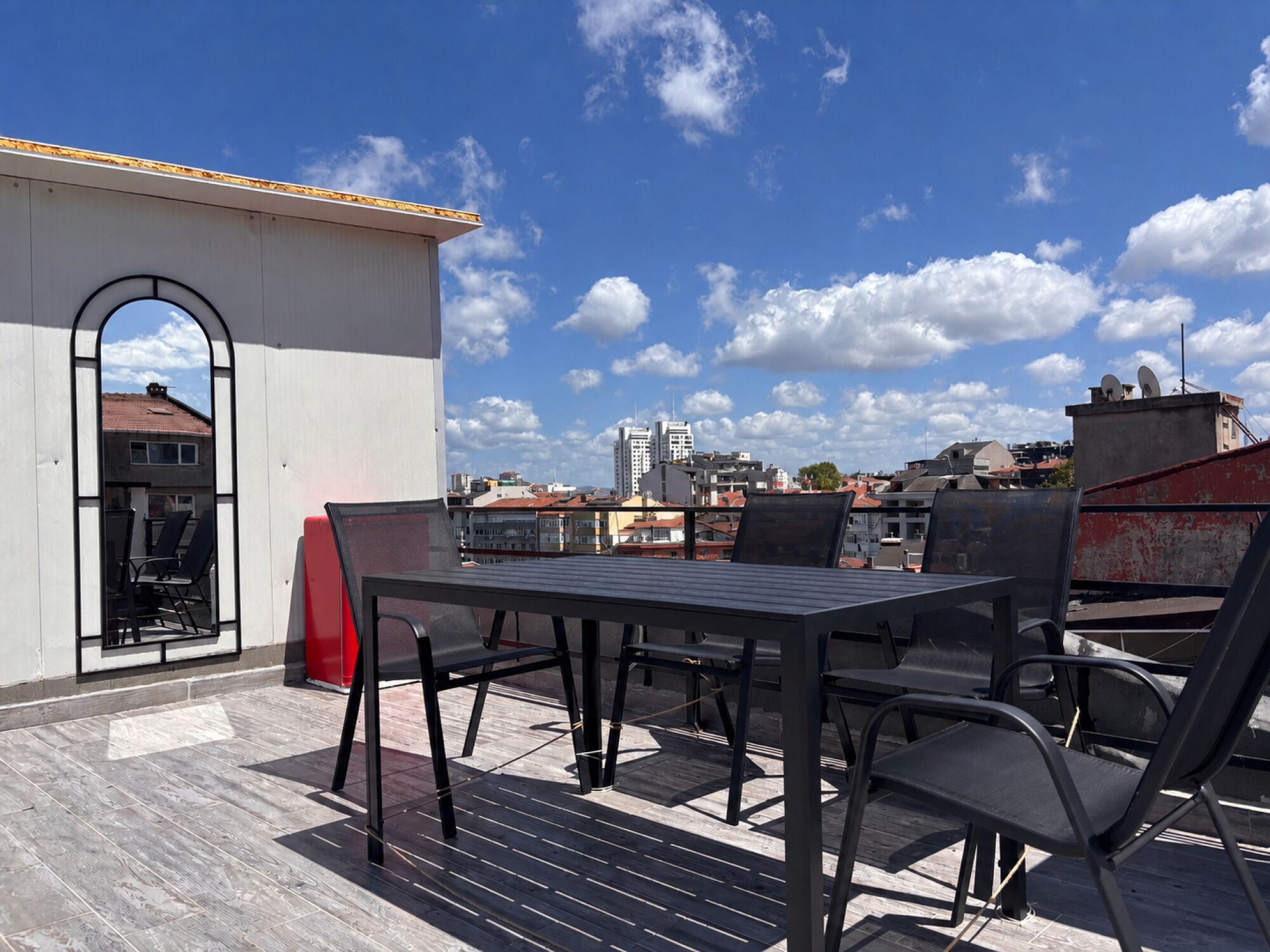 Een dakterras met een tafel en stoelen, een uitzicht op de stad en een heldere lucht.