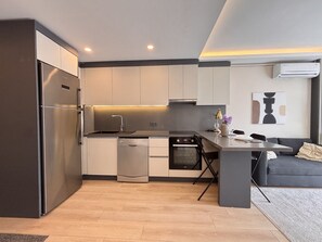 A modern kitchen with a built-in oven, dishwasher, and a dining area with a sofa and table. - Chic & Cozy 2BR – Nişantaşı (Istanbul)