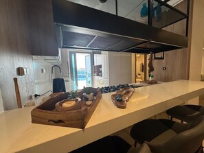 A modern kitchen with a long countertop, wooden serving tray with food items, and a built-in stove. - 2-bedroom apartment in lovely Lac 2 with AC and comfort (lac 2)