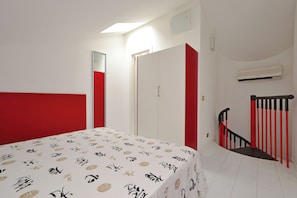 A bedroom with a bed, a wardrobe, a staircase, and an air conditioning unit. - Two Level Flat With Balcony (Lignano Sabbiadoro)