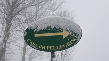 Un panneau indicateur recouvert de neige, portant l’inscription « CASA del PELLEGRINO » et une flèche pointant vers la droite.