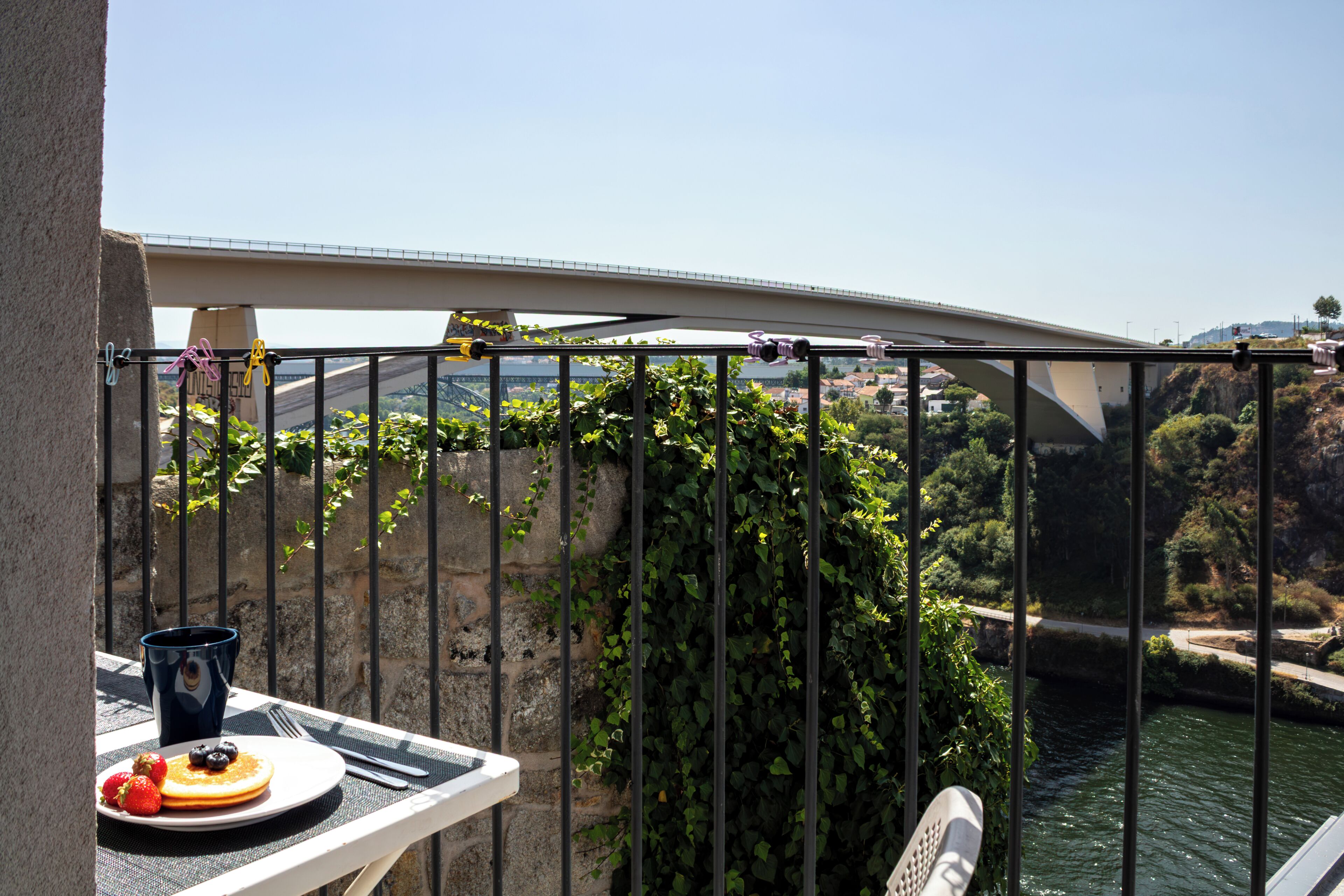 Ein Balkon mit gedecktem Tisch für das Frühstück, mit Blick auf einen Fluss und eine Brücke.