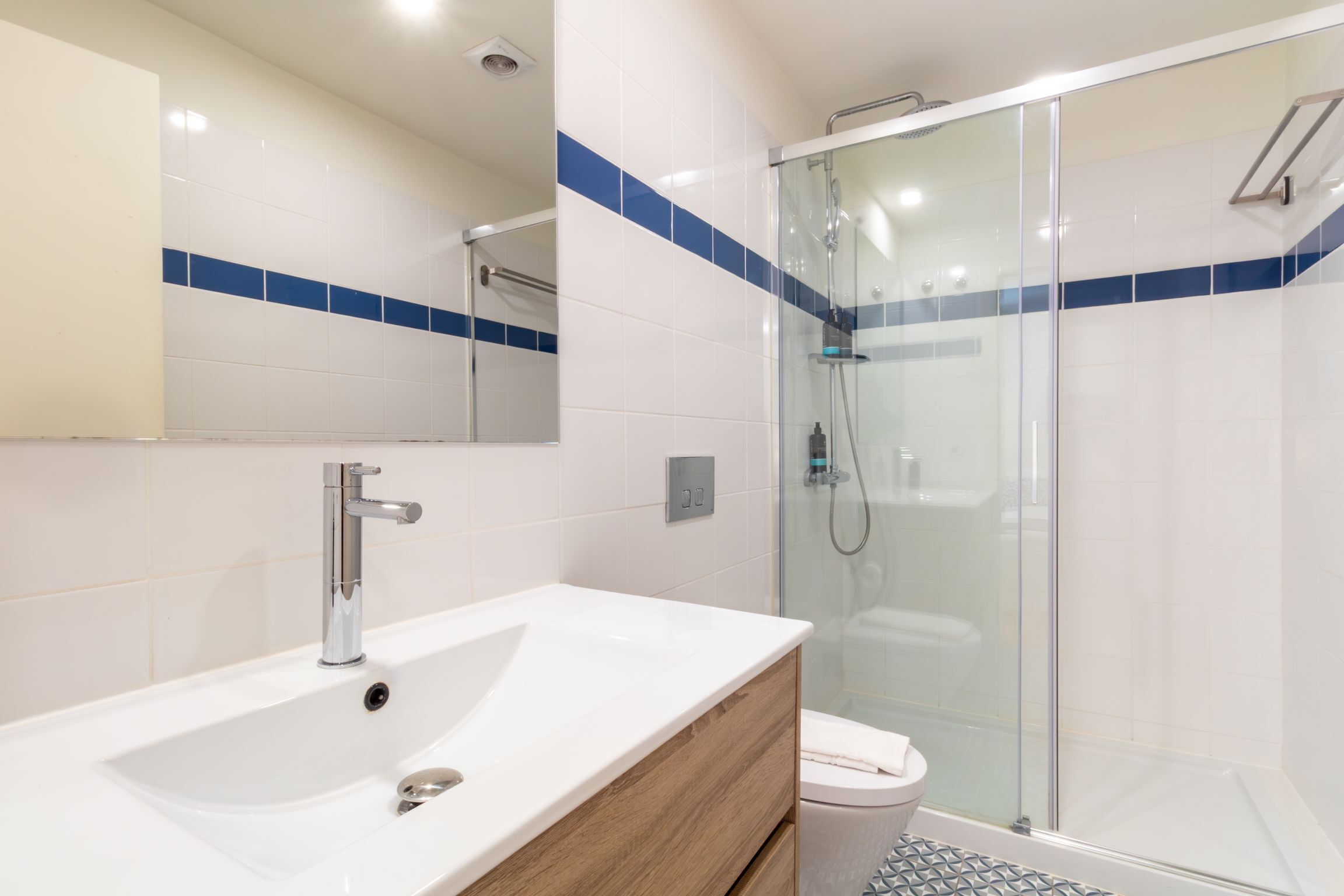 Ein modernes Badezimmer mit Waschbecken, Spiegel und Duschkabine aus Glas.