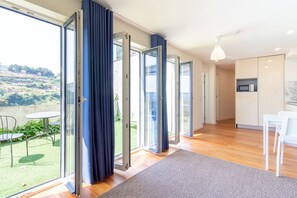 A modern interior with a kitchen, dining area, and a balcony with a view of the countryside. - Corticeira Living (Porto)