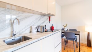 A modern kitchen with a marble countertop, stainless steel sink, and a built-in stove. - Corticeira Living (Porto)