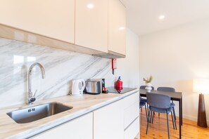 A modern kitchen with a marble countertop, stainless steel sink, and a built-in stove. - Corticeira Living (Porto)