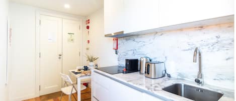 A compact kitchen with a marble countertop, stainless steel sink, and modern appliances.